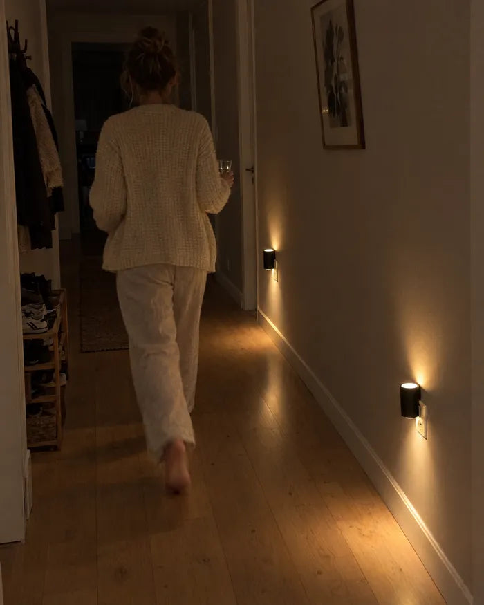Donna che attraversa un corridoio buio illuminato da applique vicino al pavimento