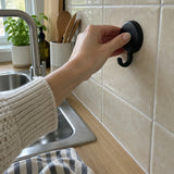 Mano che fissa un gancio Wove nero su piastrelle beige della cucina